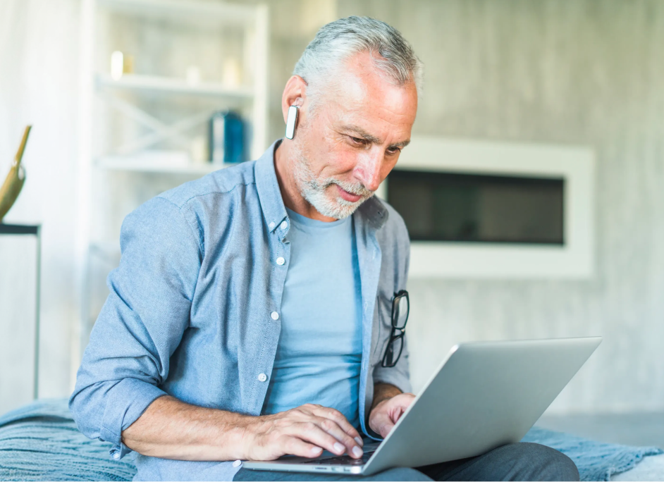 Older man reviewing paperwork on a laptop at home