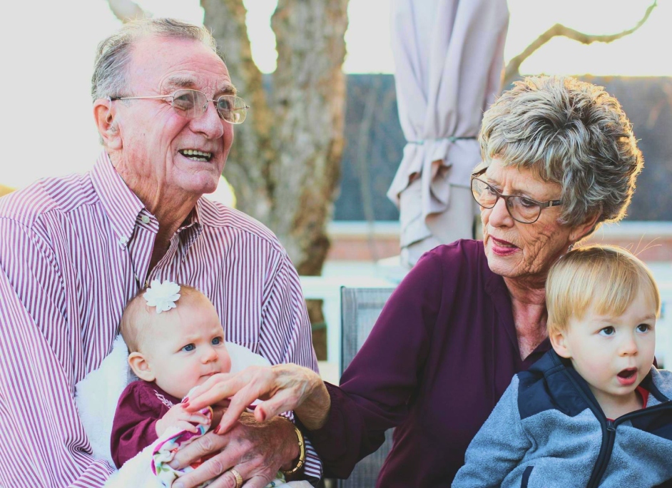 Older couple smiling with their grandchildren at home