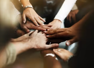 Several colleagues stacking their hands together in a team huddle